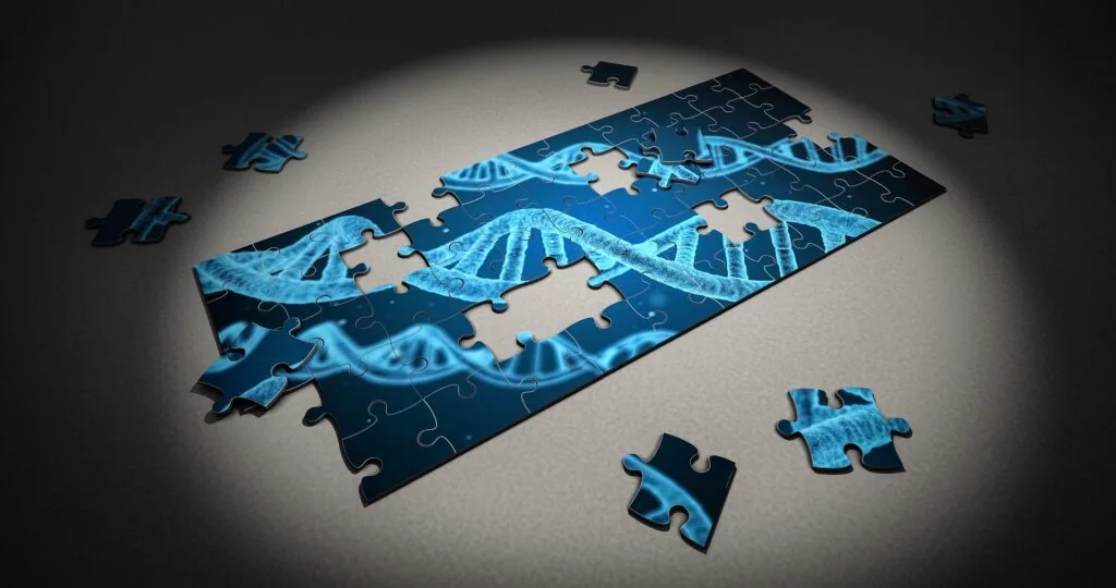 Assembled and scattered blue jigsaw puzzle pieces featuring DNA helix patterns on white surface