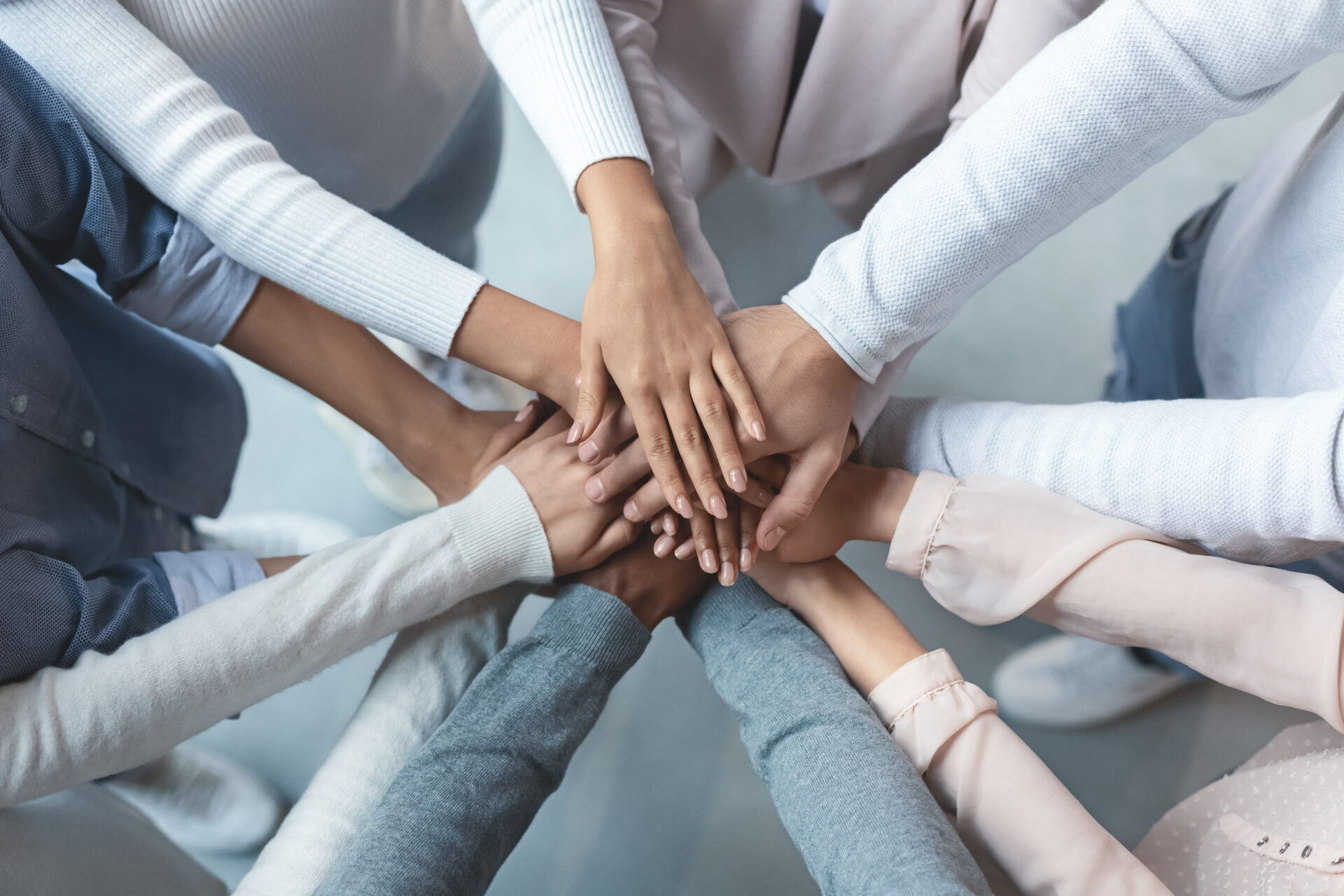 Multiracial business team putting hands on top of each other Top view of multiracial business team demonstrating cooperation with putting their hands together on top of each other