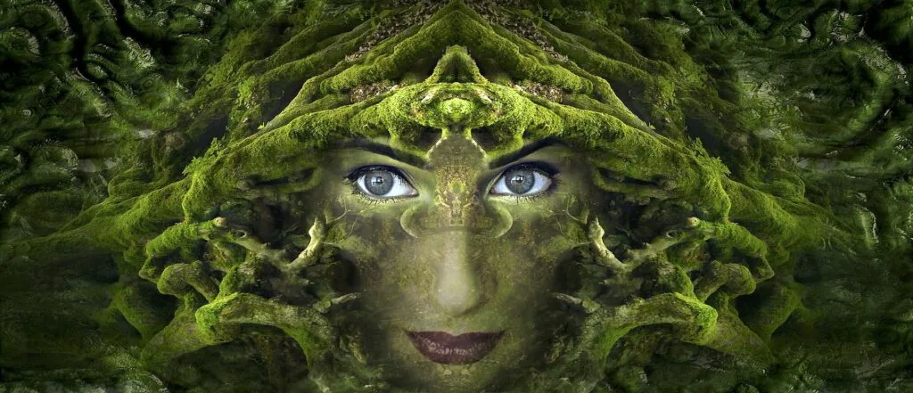 Digital art of a face with blue eyes overlaid with green moss and forest texture, creating a mystical nature-inspired effect