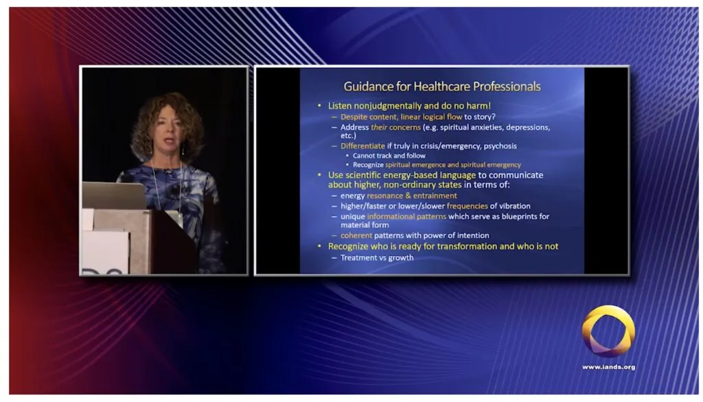 Speaker at podium presenting healthcare guidance with text overlay on blue and red gradient background