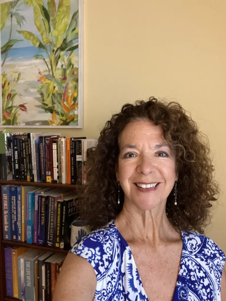 Valerie Varan smiling in front of her bookshelf of physics and consciousness books