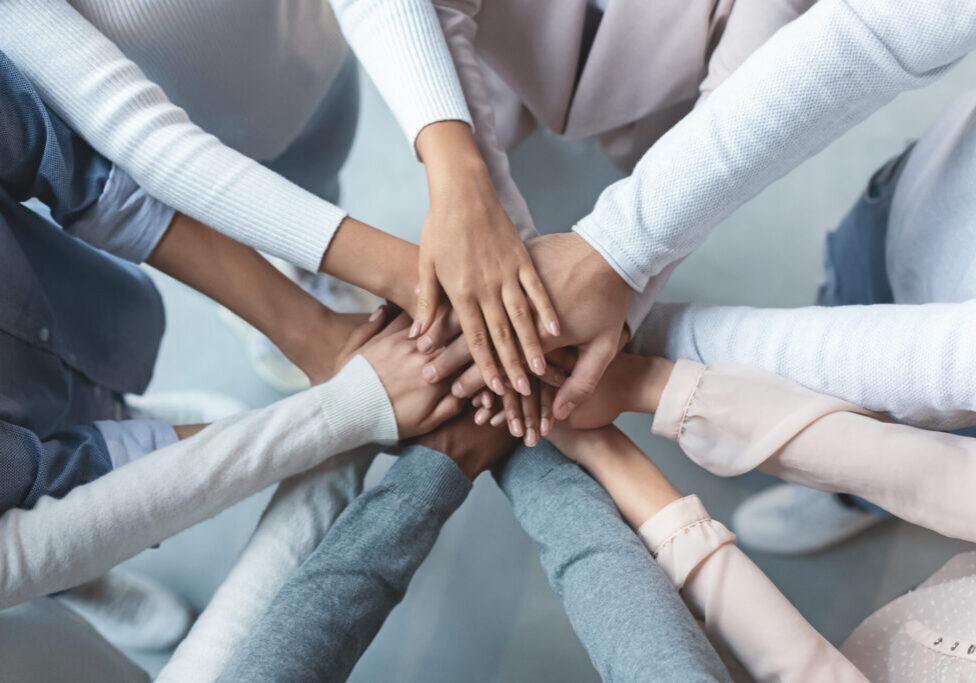 Top view of multiracial business team demonstrating cooperation with putting their hands together on top of each other